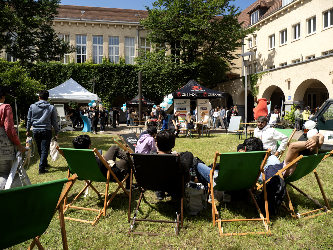 grüner Innenhof mit Pavillons eines Festes und Studierenden in Sommerliegen