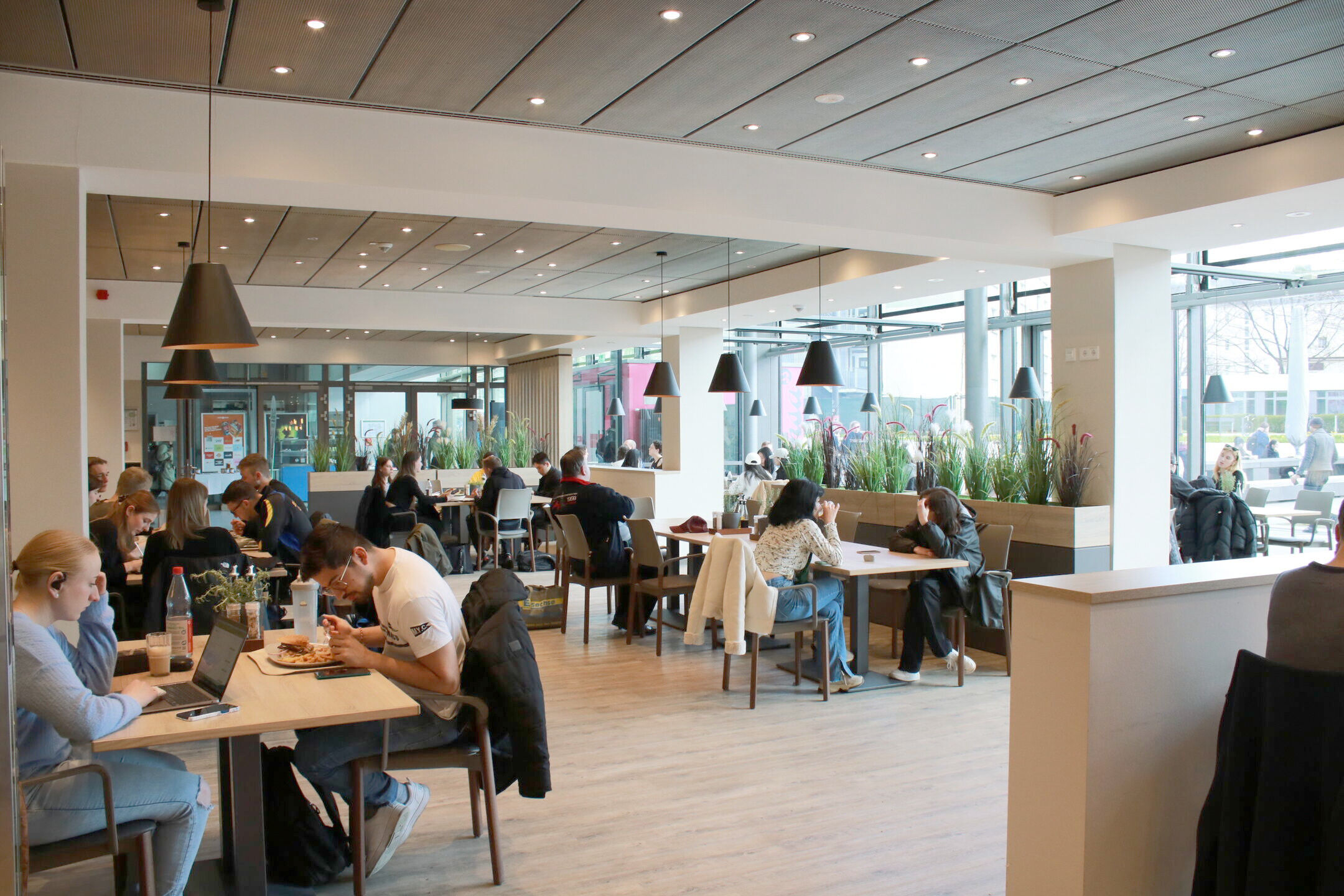 moderner Speisesaal mit Gästen die essen oder am Laptop arbeiten