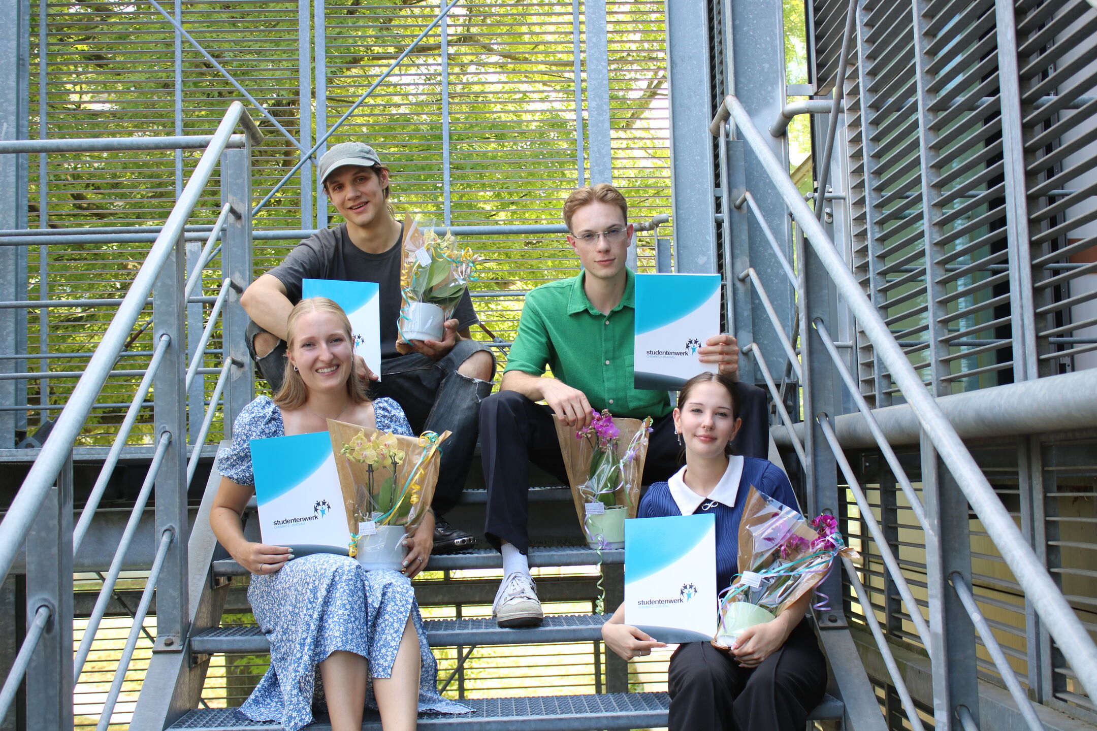 Four skilled workers with certificates and flowers
