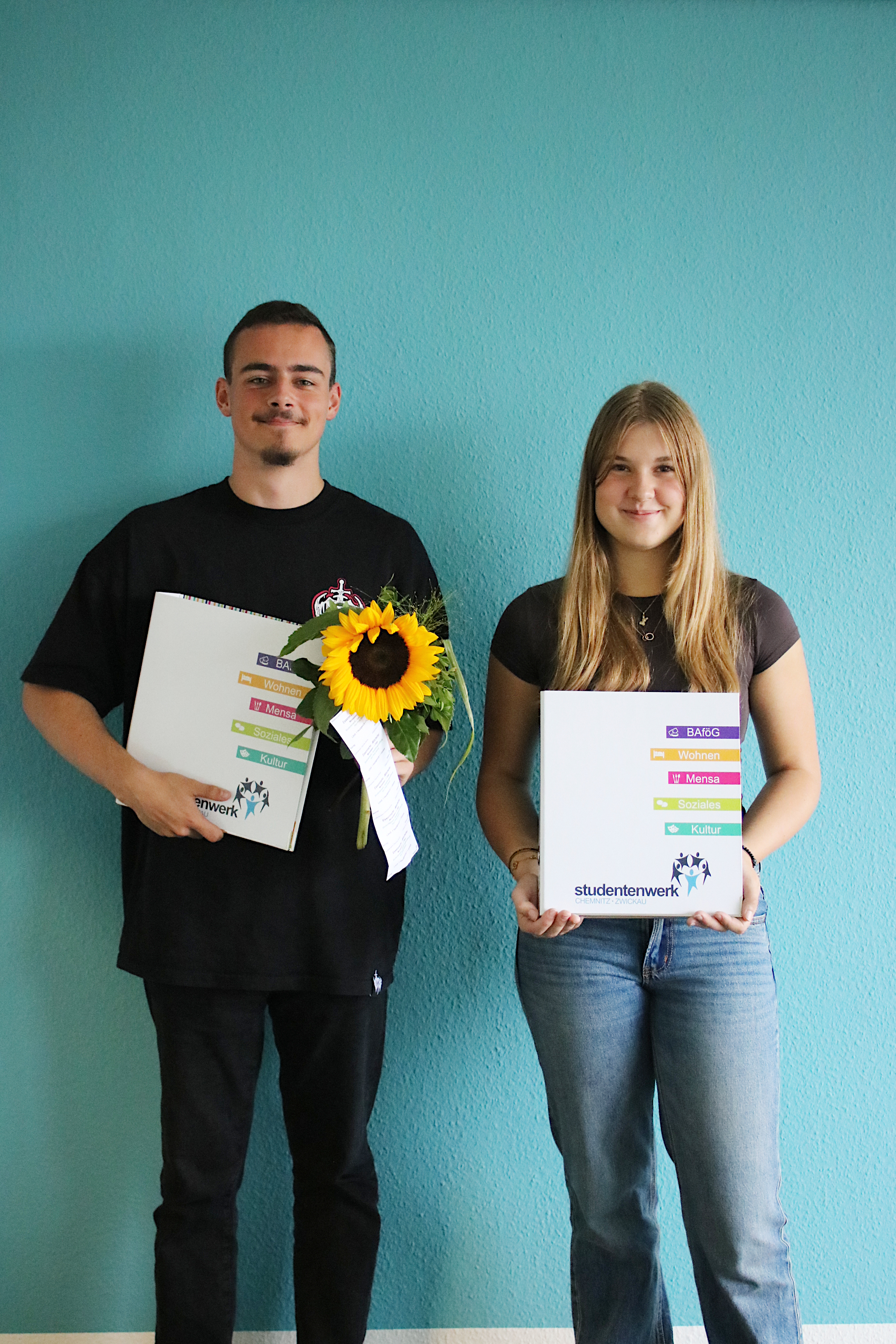 Two teenagers holding flowers and a portfolio as they start their apprenticeships