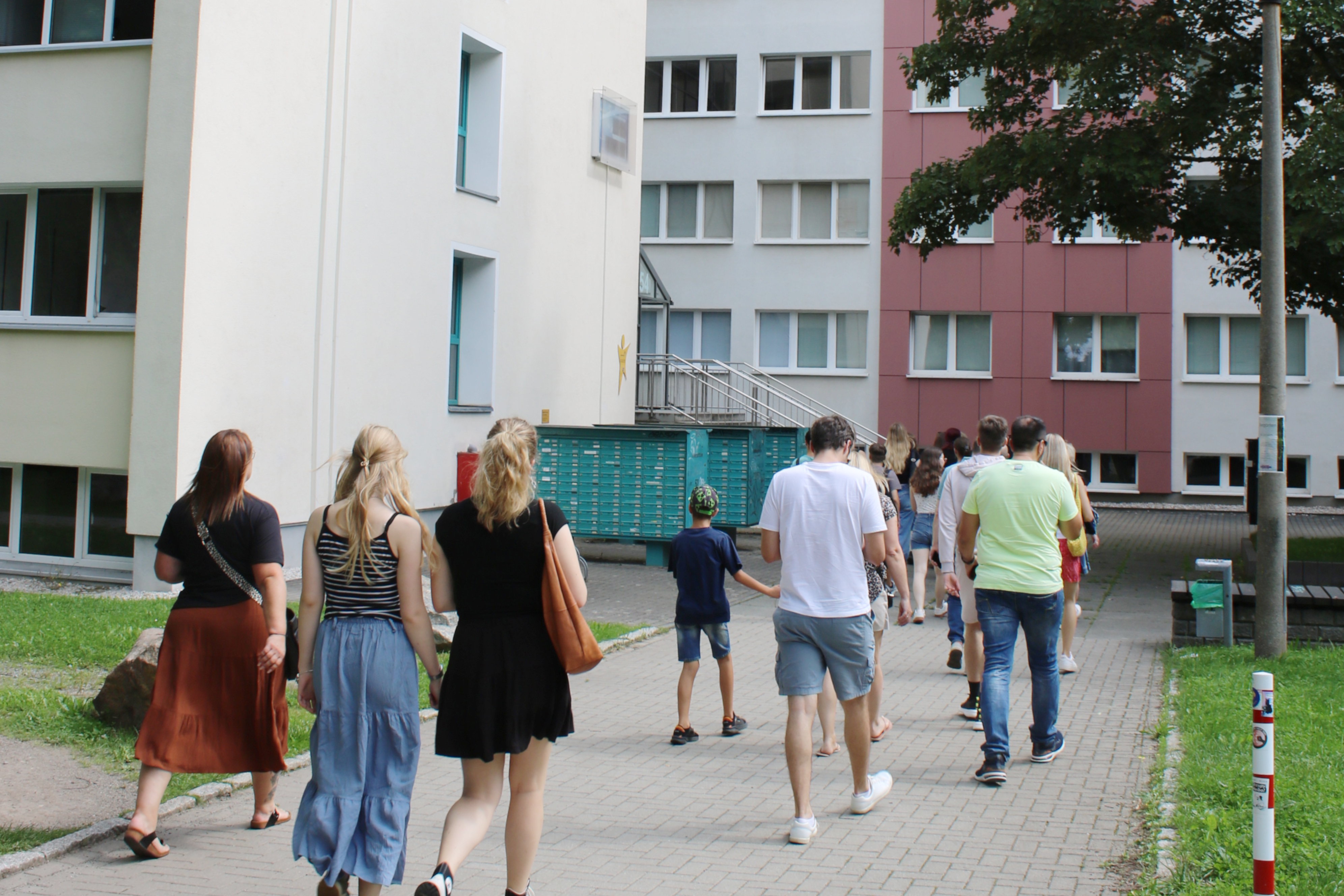 eine Gruppe Menschen läuft in ein Wohnheim