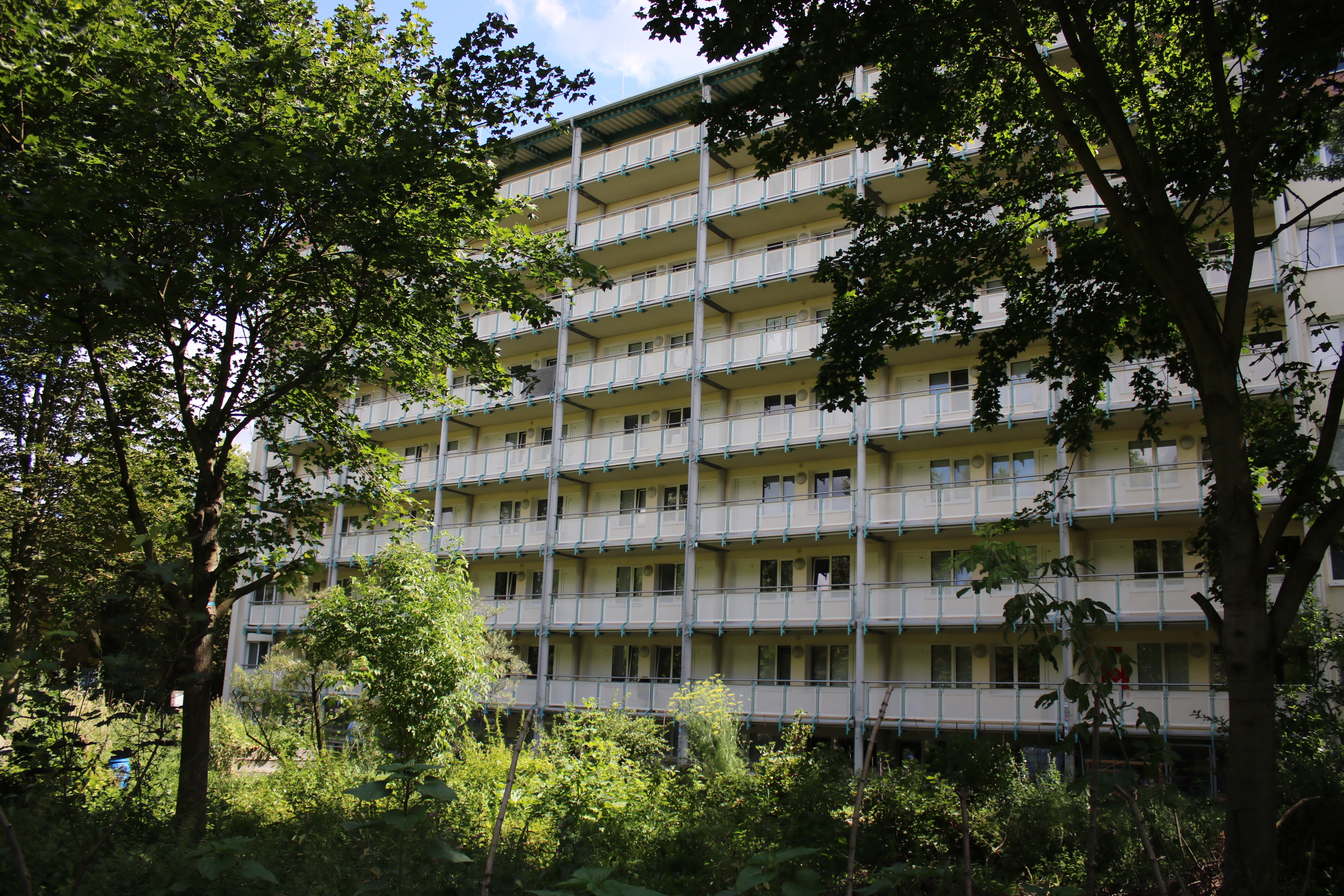 Wohnheim mit Balkongang außen herum inmitten von grünen Bäumen