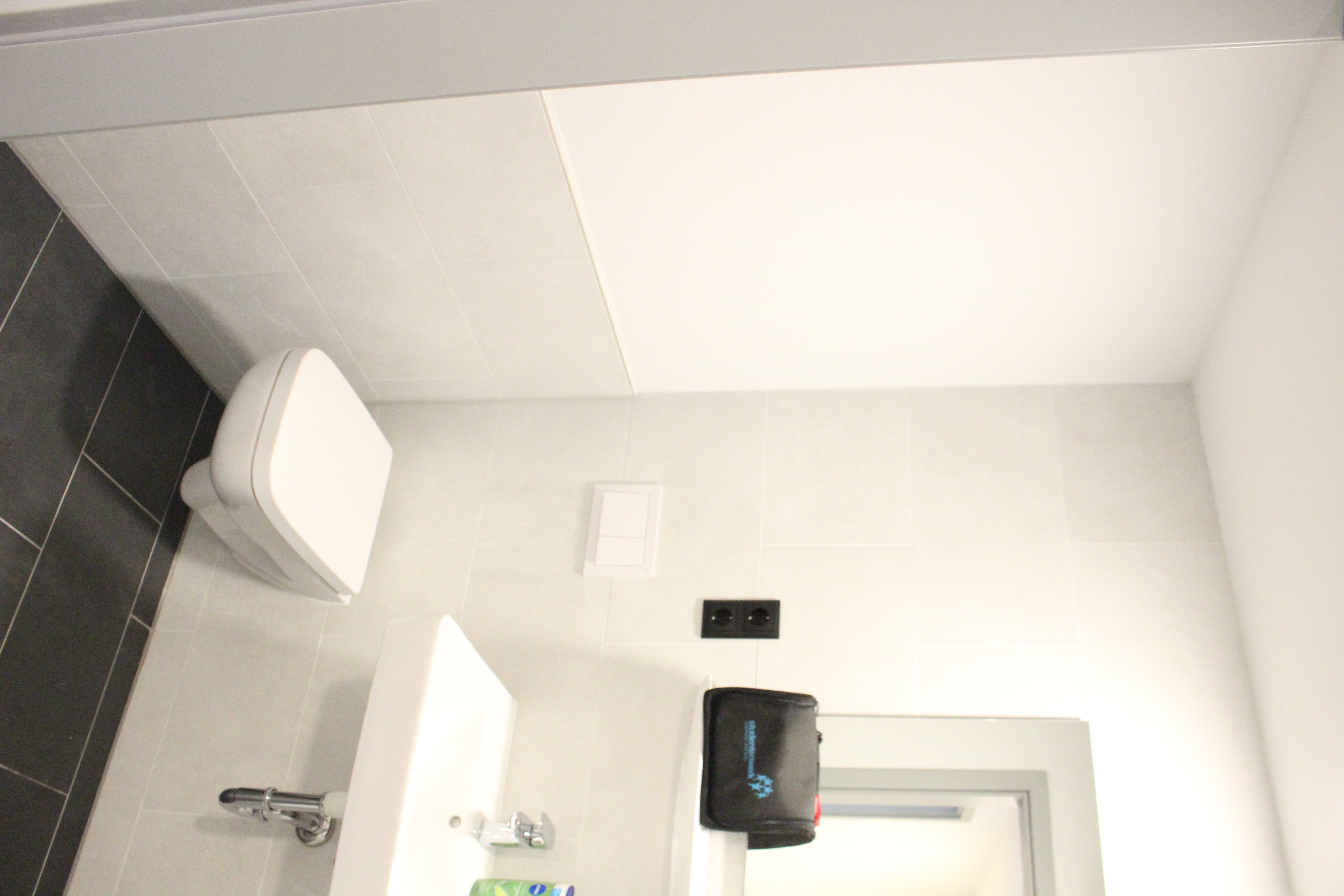 Toilette, Waschbecken, helle Fliesen, dunkler Boden