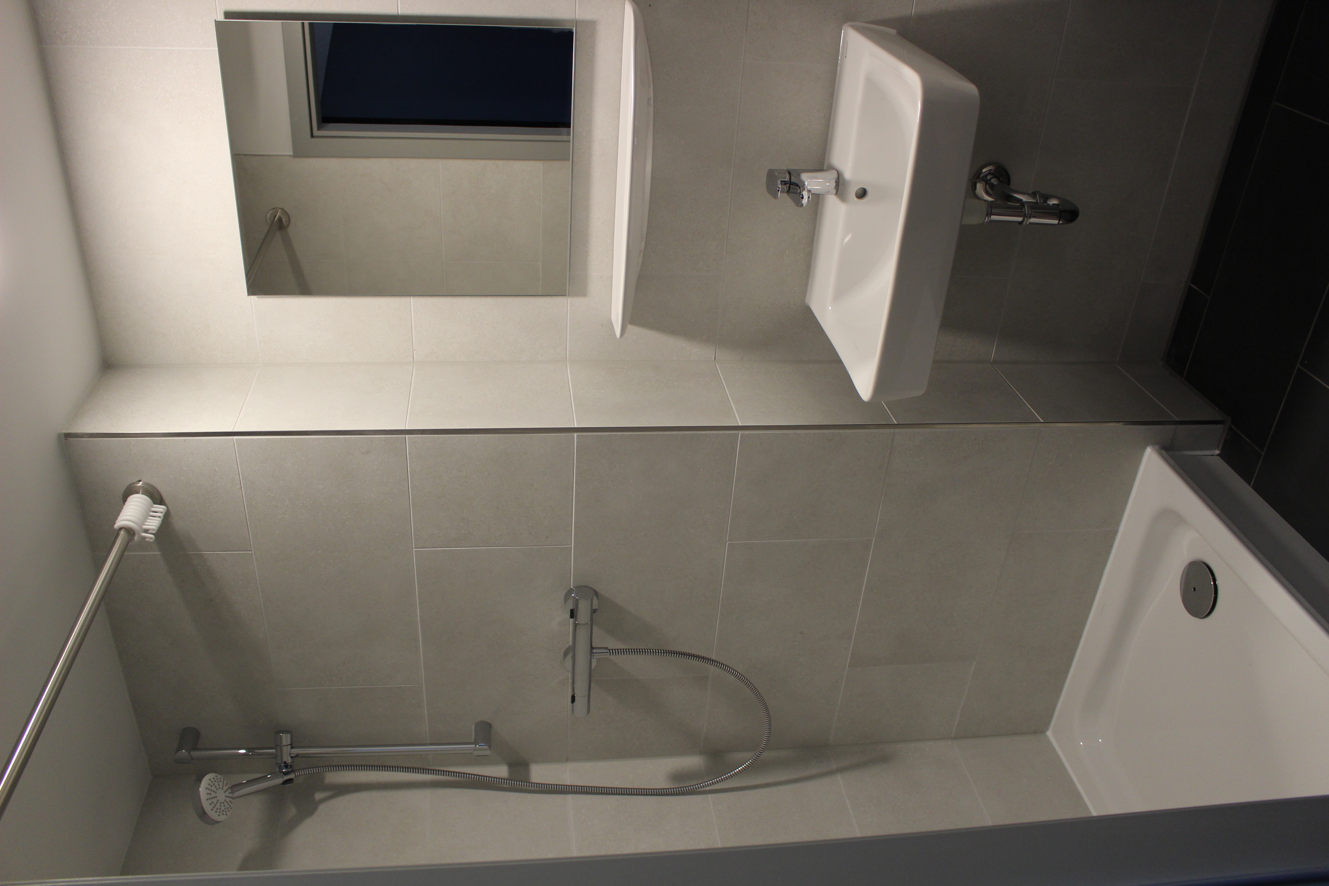 A modern, grey-tiled bathroom with a shower